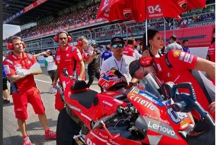 Mugiyono (kemeja putih) saat mendampingi pebalap tim Ducati, Andrea Dovizioso, sebelum balapan. Sejak 2016, Mugiyono bekerja sebagai racing service helm KYT di MotoGP. (Sumber foto: Tangkapan layar Instagram @mugiyononathania)