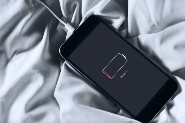 Ilustrasi charging iPhone di atas kasur