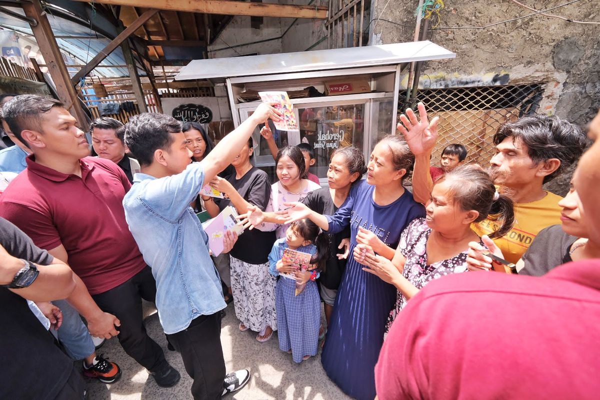 Calon wakil presiden (cawapres) nomor urut 2 Gibran Rakabuming Raka membagikan buku dan susu kepada ibu-ibu saat menyusuri gang 16, Rukun Tetangga (RT) 07, Rukun Warga (RW) 13 dalam agenda  blusukan ke gang-gang di Kelurahan Warakas, Jakarta Utara (Jakut).