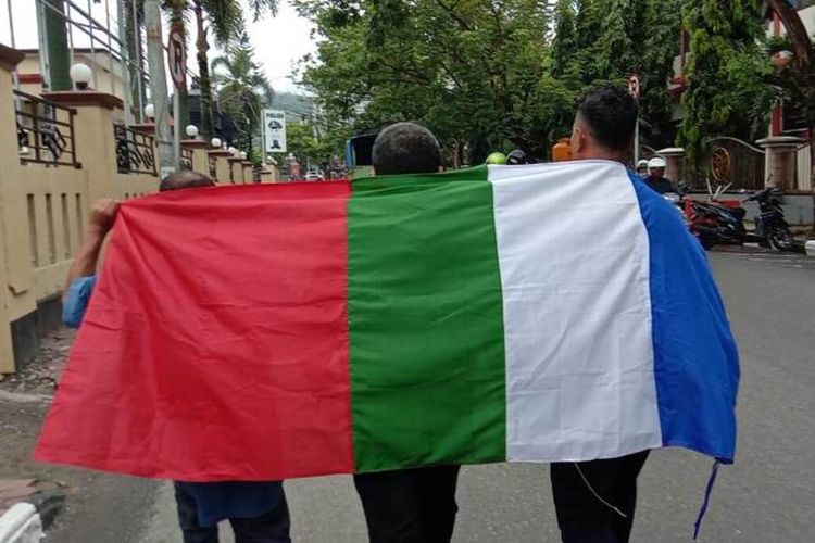 Tiga aktivis Front Kedaulatan Maluku (FKM) membawa bendera benang raja melintasi depan Kantor Polda Maluku tepat di hari ulang tahun (HUT) RMS, Kamis (25/4/ 2020)