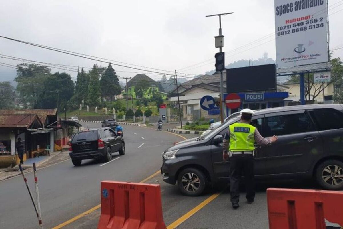 Anggota polisi di Cianjur, Jawa Barat, menghalau kendaraan dari arah Bogor yang hendak masuk ke wilayah Kabupaten Cianjur melalui jalur Puncak.