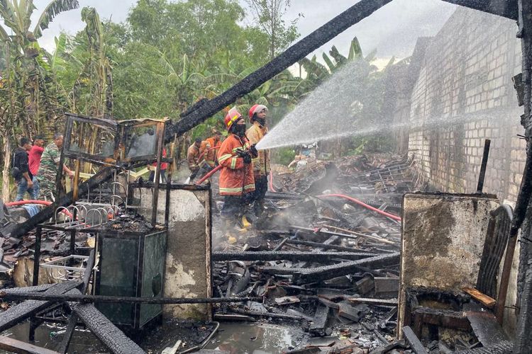 Petugas Damkarla Gresik saat proses pembasahan usai kebakaran yang melanda rumah Pardi di Desa Karangan, Kecamatan Benjeng, Gresik, Jawa Timur, Jumat (27/1/2023).