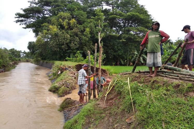 Warga bergotong royong membenahi tanggul Sungai Bendokrosok di Desa Mojoagung yang jebol, Kamis (4/2/2021). Jebolnya tanggul ini menyebabkan ratusan rumah terdampak luapan air semalam.