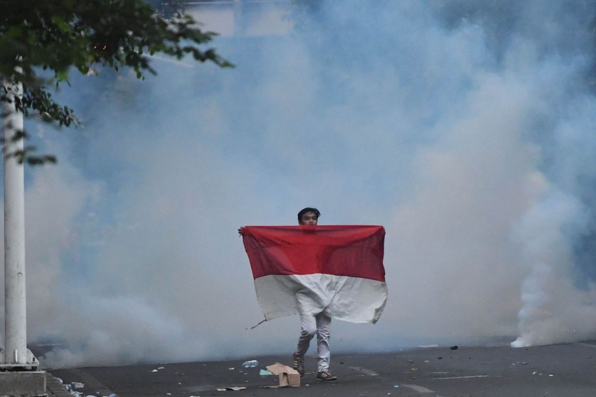 Seorang pengunjuk rasa yang menolak UU KPK hasil revisi dan RUU KUHP membawa bendera Merah Putih di kawasan dekat Kompleks Parlemen, Senayan, Jakarta, Senin (30/9/2019). ANTARA FOTO/Akbar Nugroho Gumay/wsj.