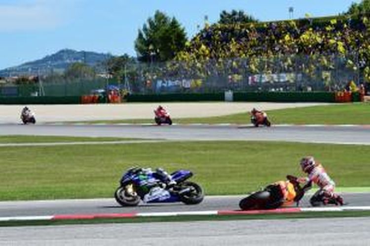 Pebalap Repsol Honda asal Spanyol, Marc Marquez (kanan) terjatuh di tikungan empat Sirkuit Misano pada putaran ke-10 GP San Marino, Minggu (14/9/2014). Pebalap Movistar Yamaha asal Spanyol, Jorge Lorenzo (kiri), melewatinya.