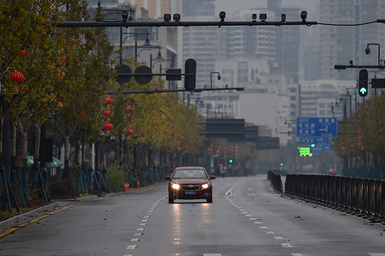 Sebuah mobil melaju sendiri di jalanan kota Wuhan, China, yang sepi akibat wabah virus corona yang mematikan, Minggu (26/1/2020). 