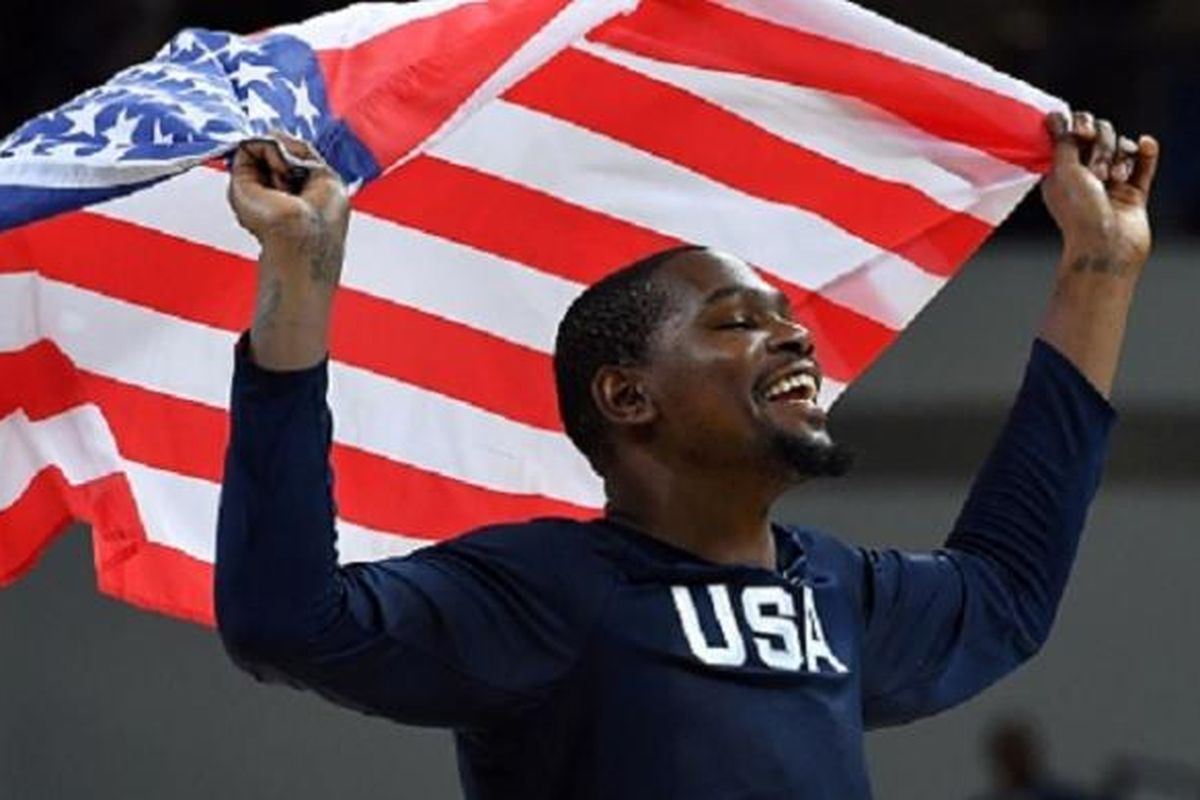 Kevin Durant mengibarkan bendera Amerika Serikat seusai timnya memenangi medali emas pada final versus Serbia, Minggu (21/8/2016). 