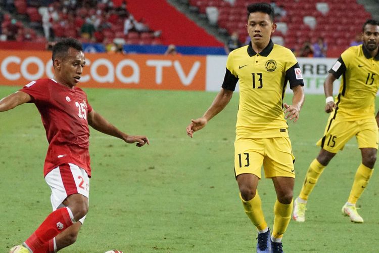 Pesepak bola Timnas Indonesia Irfan Jaya (kiri) berusaha melewati pesepak bola Timnas Malaysia Arif Aiman (tengah) dalam pertandingan grup B Piala AFF 2020 di National Stadium, Singapura, Minggu (19/12/2021). Indonesia menang dengan skor 4-1 dan lolos ke babak semifinal Piala AFF.