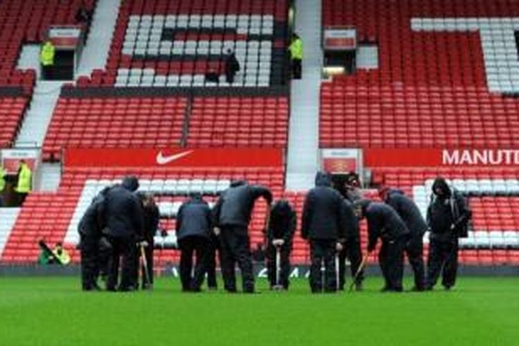 Para pekerja sedang mengurus lapangan Stadion Old Trafford.