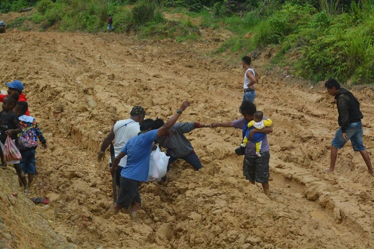 Para penumpang mobil daubel gardan yang dievakuasi keluar dari ruas jalan Trans-Papua Barat yang rusak di Kampung Memey, Distrik Tahota, Kabupaten Manokwari Selatan, Papua Barat.