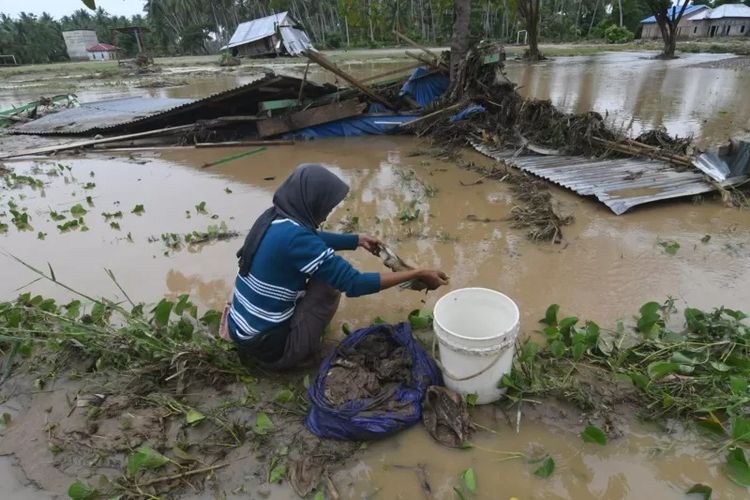 Warga membersihkan pakaian bayi yang terendam lumpur akibat diterjang banjir bandang di Desa Torue, Kabupaten Parigi Moutong, Sulawesi Tengah, Jumat (29/7/2022).