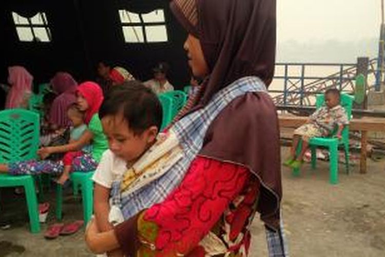 Muhammad Faiza (11 bulan) saat digendong ibunya, Sit Fatimah, menunggu giliran pengobatan di posko bakti sosial pelayanan kesehatan korban kabut asap di Palangkaraya, Kalimantan Tengah. (27/10/2015)