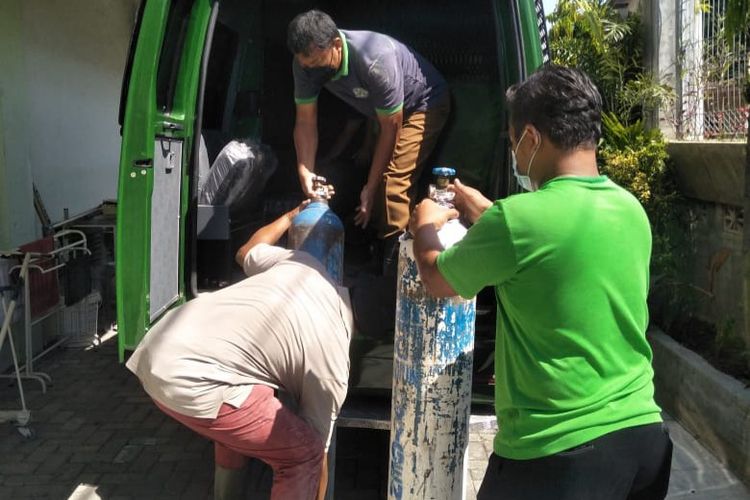 MASUKAN TABUNG—Petugas PT Samator memasukkan tabung kosong yang sudah diisi oksigen medis ke mobil tahanan milik Kejaksaan Negeri Kota Madiun untuk dibawa ke Rumah Sakit Santa Clara Kota Madiun, Senin (26/7/2021).