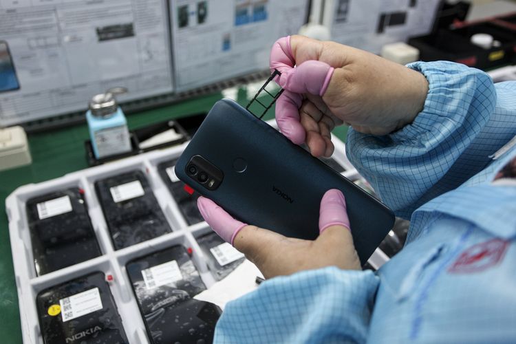 Pemasangan komponen slot kartu SIM dan microSD ke dalam perangkat Nokia di pabrik milik PT Sat Nusapersada, Batam. Para pekerja harus menggunakan sarung jari agar komponen tidak terkontaminasi oleh suhu tubuh manusia.
