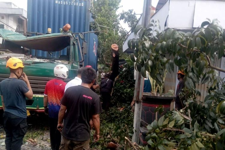 Truk trailer yang mengangkut kontainer barang tersangkut ranting pohon di Jalan Jati, Kota Blitar, Rabu (5/7/2023). Kecelakaan itu mengakibatkan kerusakan parah pada kabin truk serta mengakibatkan pohon mahoni tumbang dan menimpa sebuah warung nasi.