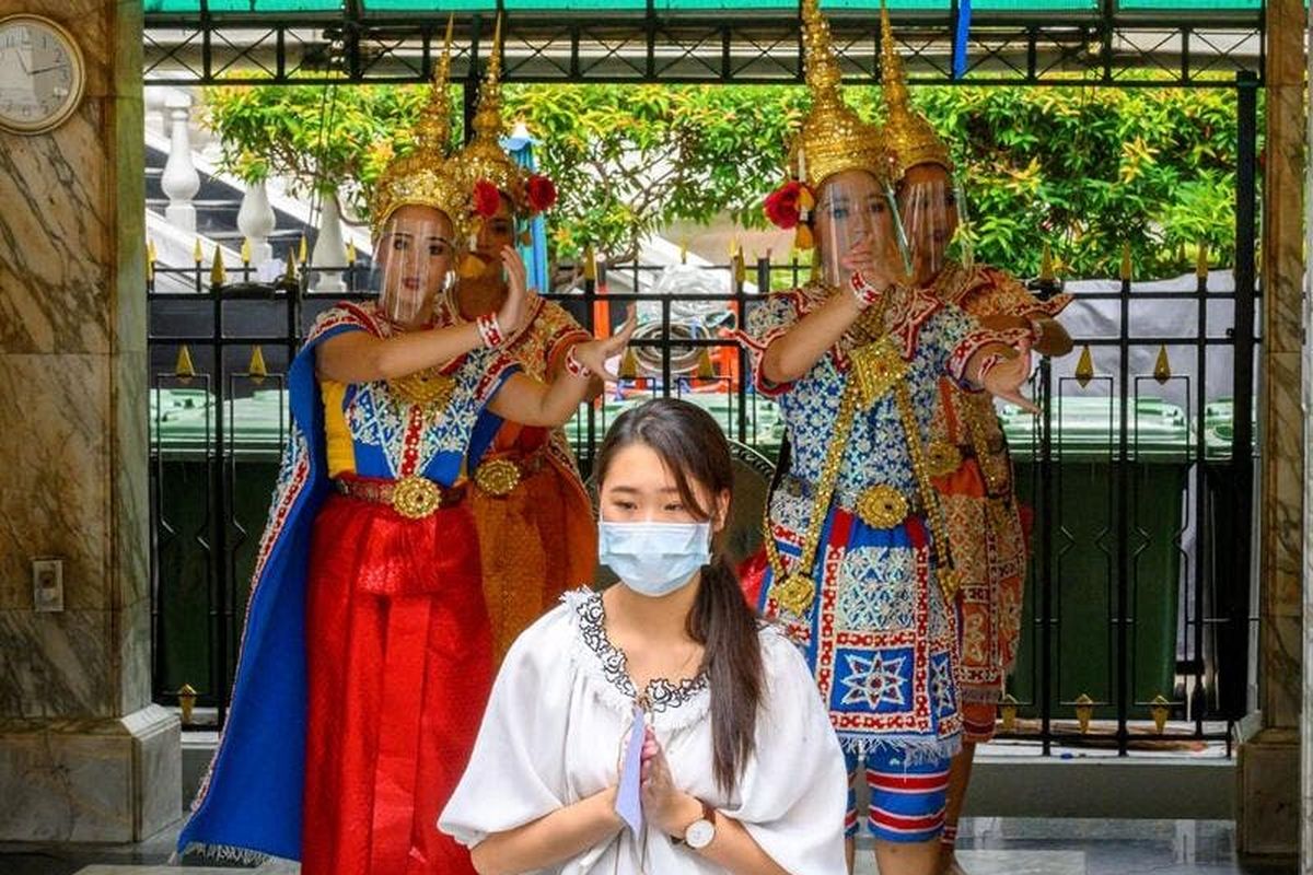 Penari tradisional Thailand yang mengenakan pelindung wajah tampil di Kuil Erawan, yang dibuka kembali setelah pemerintah Thailand melonggarkan langkah-langkah untuk memerangi penyebaran coronavirus novel COVID-19, di Bangkok pada 4 Mei 2020. Thailand mulai melonggarkan pembatasan terkait dengan COVID -19 pada 3 Mei dengan memungkinkan berbagai bisnis untuk dibuka kembali, tetapi memperingatkan bahwa langkah-langkah yang lebih ketat akan diberlakukan kembali jika kasus meningkat lagi.