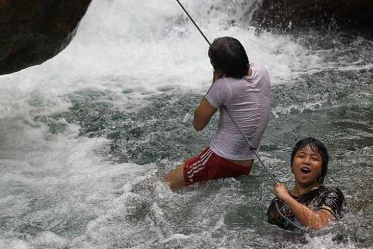 Dua pengunjung berpegang pada tambah yang telah disediakan warga untuk bertahan dari arus curug yang deras di Curug Ciburial, Desa Cibadak, Bogor, Jawa Barat.
 
