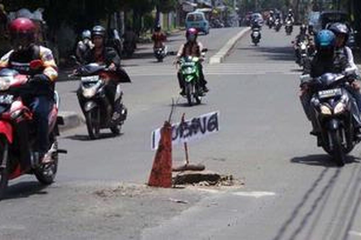 Pengendara motor menghindari jalan berlubang di Pejaten Barat, Pasar Minggu. Kamis (7/2/2013)