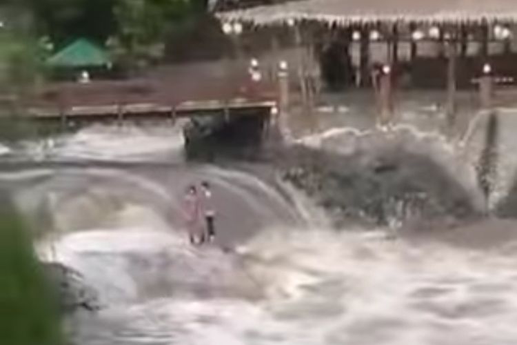 Tangkapan layar video yang memperlihatkan dua orang terjebak di Sungai Banjaran dekat obyek wisata Curug Bayan, Baturraden, Kabupaten Banyumas, Jawa Tengah, Senin (6/6/2022) sore.