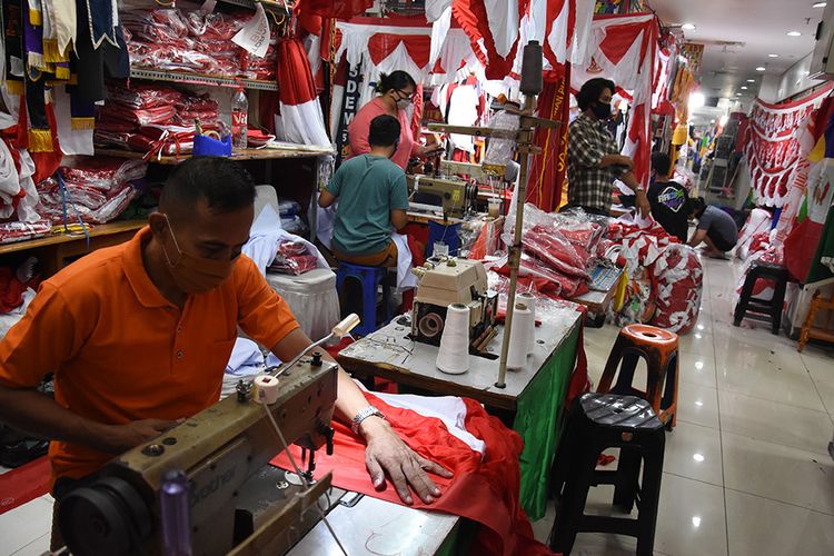 Pekerja menjahit bendera merah putih di kiosnya di kawasan Pasar Senen, Jakarta, Selasa (4/8/2020). Menjelang peringatan HUT ke-75 Kemerdekaan Republik Indonesia, sejumlah pedagang mengaku penjualan pernak-pernik bendera merah putih mengalami penurunan 50 persen dibanding tahun lalu atau dari produksi 80 bendera per hari menjadi 40 bendera per hari akibat pandemi Covid-19.