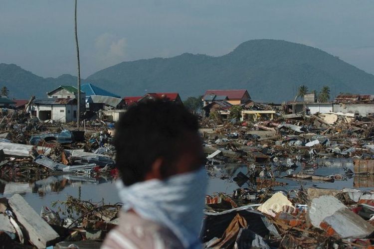 Warga melintas di permukiman yang hancur tersapu gempa dan gelombang tsunami di Lampare Kota, Banda Aceh, Provinsi Nanggroe Aceh Darussalam, Selasa (28/12). 