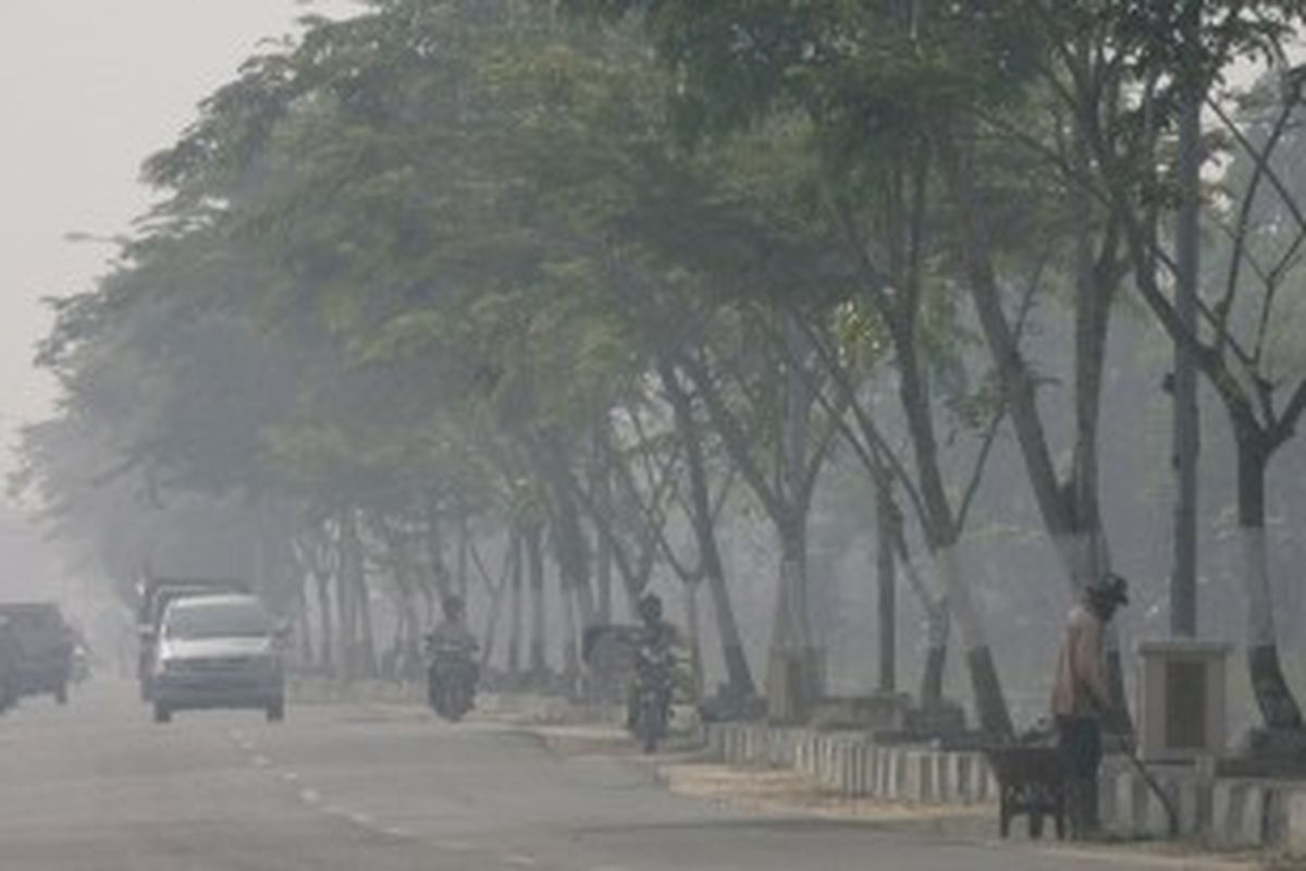 Warga tetap melakukan aktivitas meskipun kabut asap terus menyelimuti kota Pekanbaru, seperti yang tampak di jalan Parit Indah, Jumat (7/8). Kebakaran hutan dan lahan masih terus terjadi di beberapa kota dan kabupaten di provinsi Riau, sehingga menyebabkan ratusan ribu siswa terpaksa diliburkan dari sekolahnya.