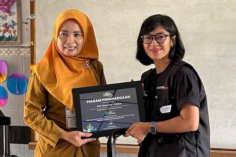 Relawan Kompas.com Inggried Dwi Wedhaswary berfoto bersama Kepala Sekolah Dasar Banaran 2 Klaten, Jawa Tengah, Rini Hastuti dalam kegiatan ekspedisi Jagat Literasi, peringatan 30 Tahun Kompas.com, Selasa (5/8/2025).