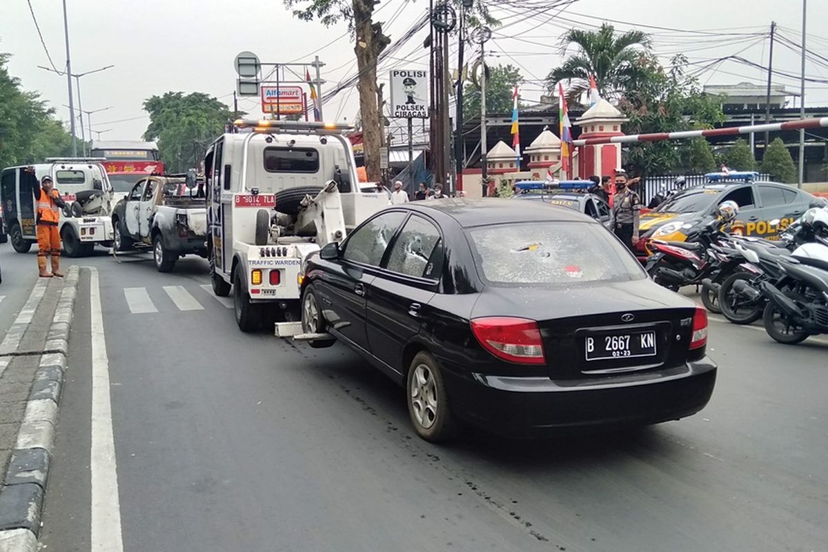 Petugas menderek dua mobil yang terbakar, dua mobil dalam kondisi pecah kaca dan satu bus operasional di Mapolsek Ciracas,  Sabtu (29/9/2020)