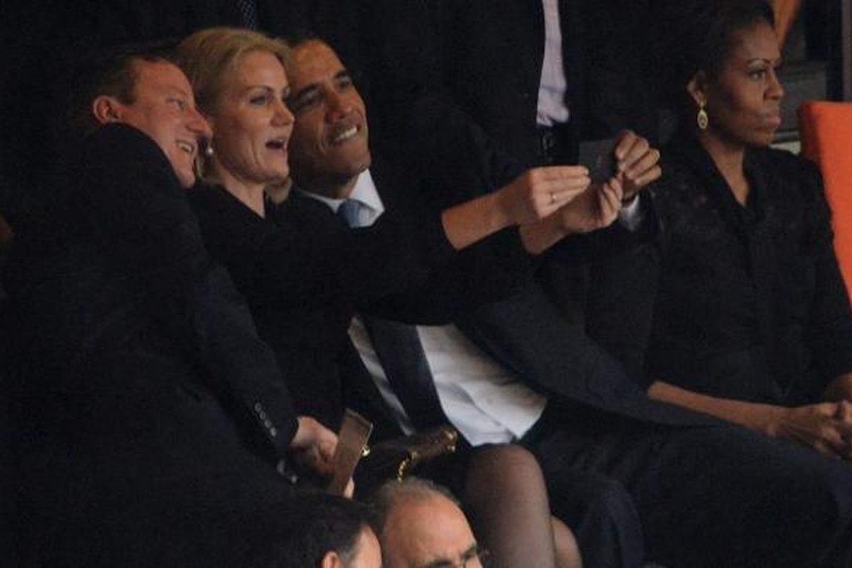 Presiden AS Barack Obama mengambil foto diri sendiri (selfi) dengan PM Inggris, David Cameron, dan PM Denmark, Helle Thorning-Schmidt saat upacara mengenang Nelson Mandela di Afrika Selatan, Selasa (10/12).