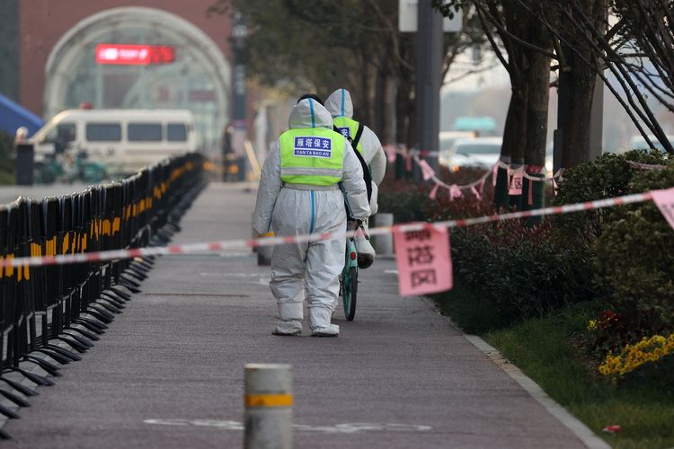 Petugas keamanan berjalan di area yang ditutup untuk menangani penyebaran Covid-19 di kota Xi'an, provinsi Shaanxi, China, Rabu (22/12/2021).