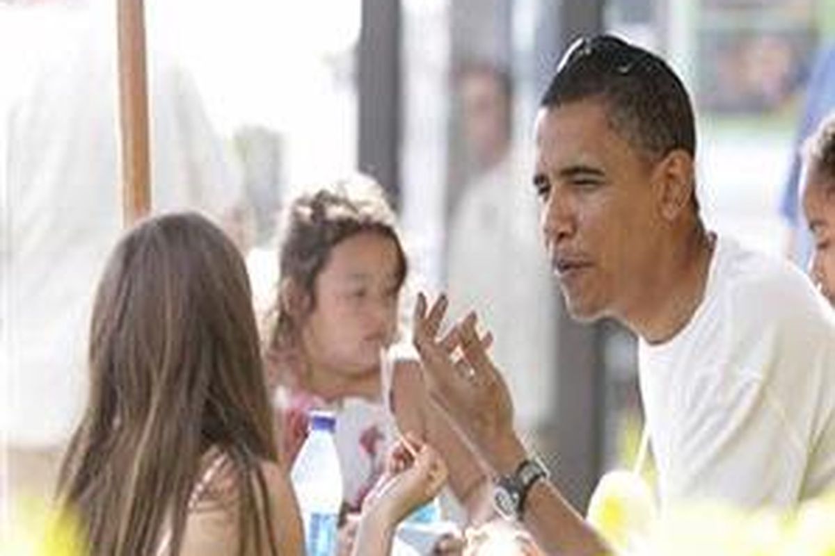 Barack Obama bercanda dengan temannya saat berlibur di Honolulu, Hawaii, Jumat (26/12).