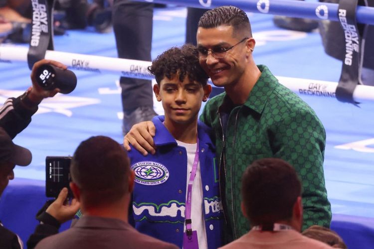 Cristiano Ronaldo berfoto dengan anaknya sebelum pertarungan tinju Day of Reckoning di KIngdom Arena, Riyadh, Arab Saudi, Minggu (24/12/2023) pagi WIB. (Photo by Fayez NURELDINE / AFP)