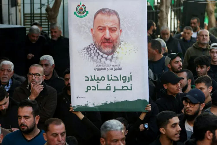Warga Palestina membawa spanduk dengan foto Arouri di tengah pemakaman Ahmad Hammoud, pejabat Hamas yang tewas terbunuh bersama Arouri.