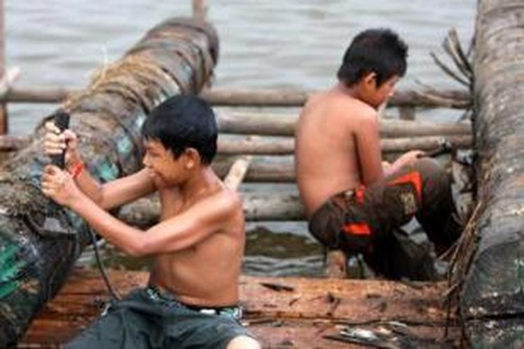 Anak-anak membersihkan meriam karbit yang terbuat dari kayu yang baru diangkat dari Sungai Kapuas di Kampung Banjar Serasan, Pontianak Timur, Kalbar, Senin (14/9/2014). Meriam karbit biasa dimainkan di tepian Sungai Kapuas sebagai tradisi untuk menyambut Hari Raya Idul Fitri.