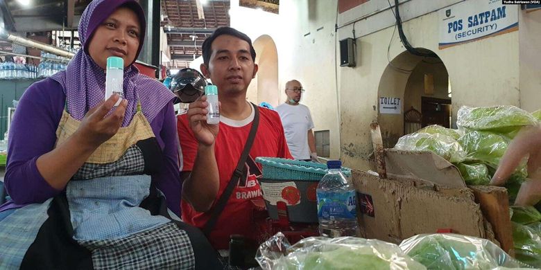 Pedagang sayur dan buah, Yatmi, dan rekannya menunjukkan hand sanitizer yang diberikan secara gratis untuk komunitas pasar tradisional di Solo, 21 Maret 2020