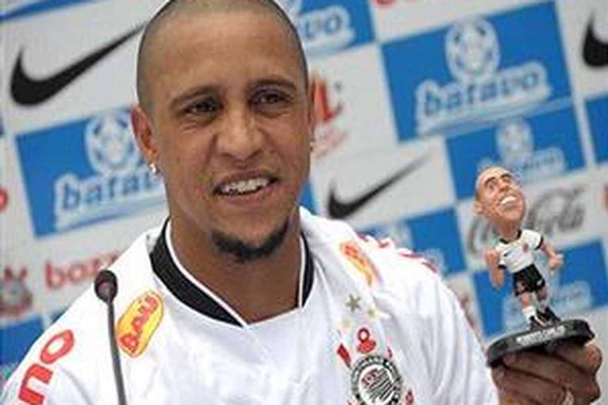 Roberto Carlos memegang boneka tiruannya saat diperkenalkan di hadapan pendukung Corinthians, Senin (4/1/2010).