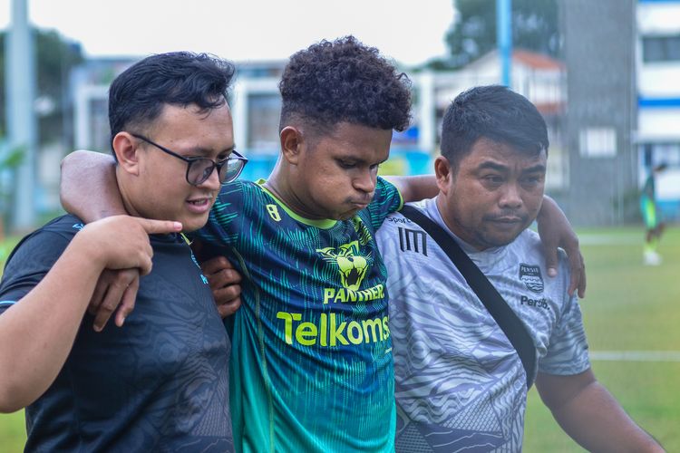 Bek Persib Bandung David Kevin Rumakiek ditopang dua tim medis Persib saat mengalami cedera dalam sesi latihan rutin tim.