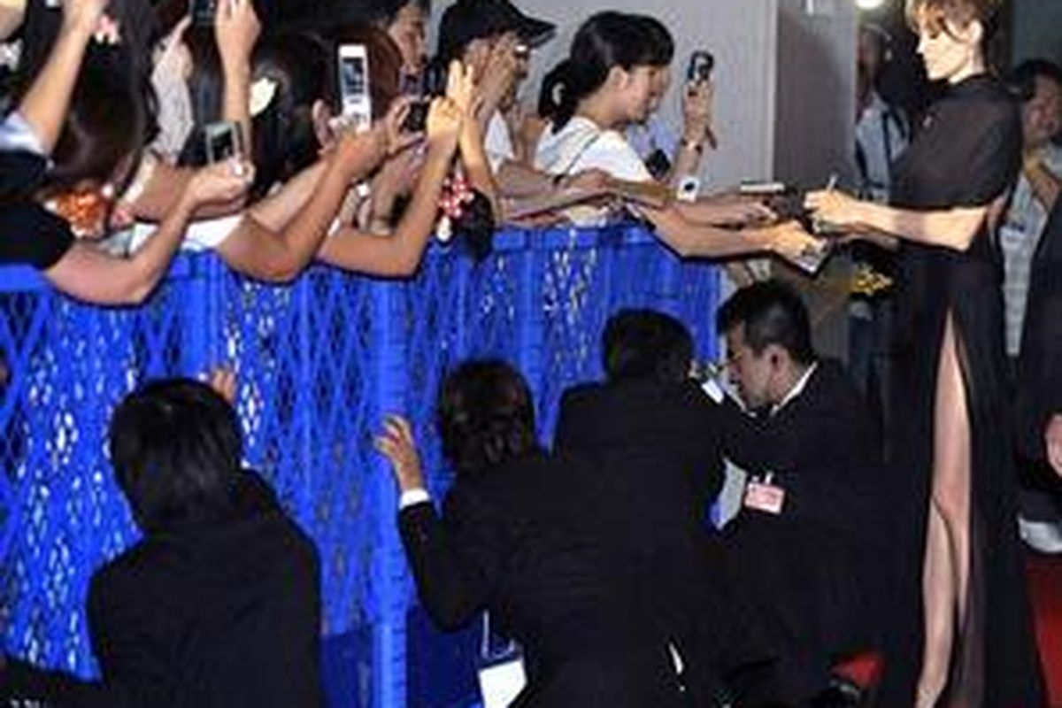 Going wild: The assembled throng take photos of Jolie as she signs autographs - while security staff help to contain the fans  