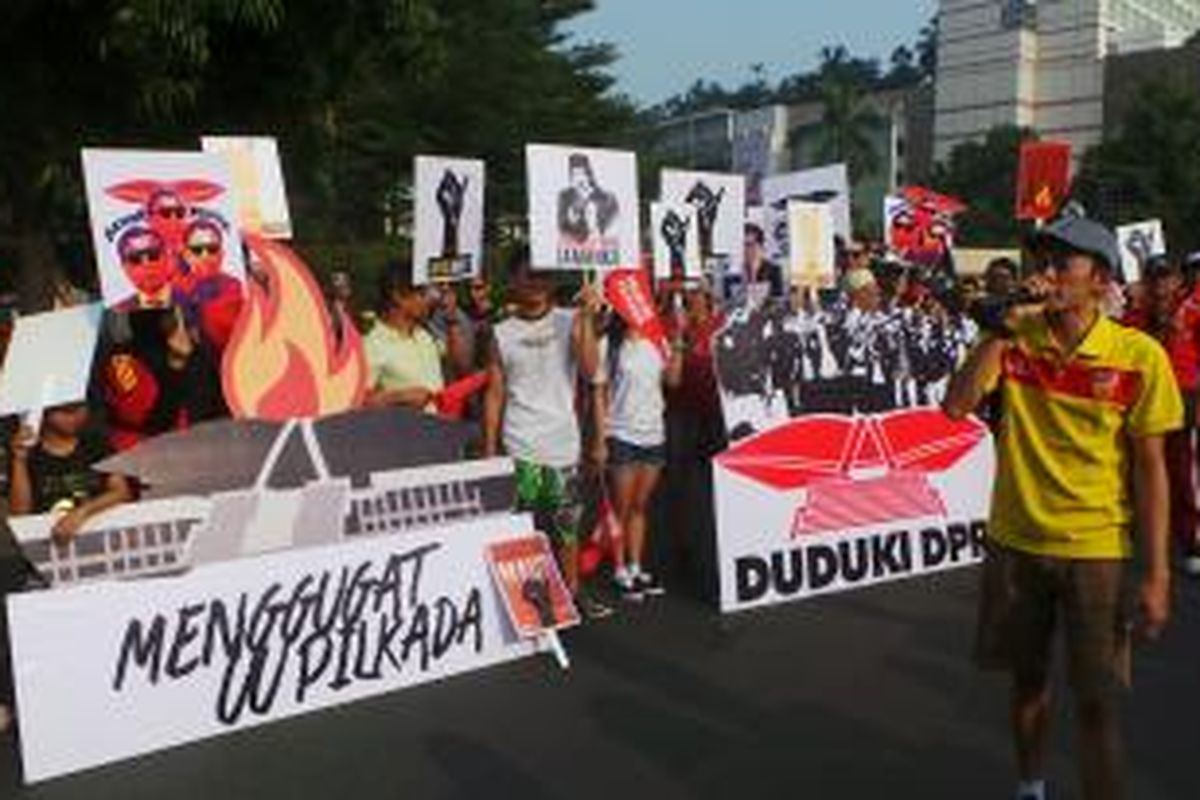 Puluhan orang yang tergabung dalam parade rakyat melakukan aksi unjuk rasa di Bundaran HI menolak pilkada langsung. Minggu (12/10/2014).