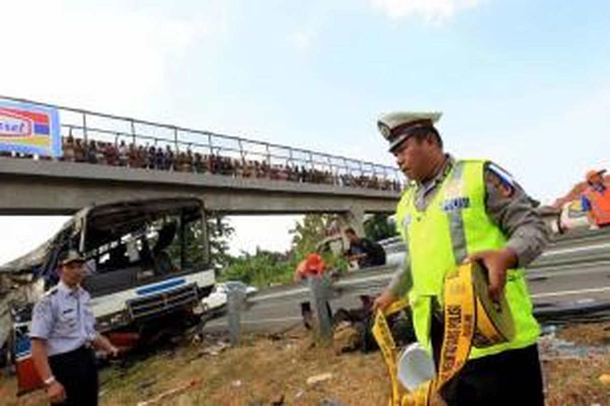 Petugas memasang garis polisi di lokasi kecelakaan bus Rukun Sayur dengan nomor polisi AD 1523 CF di kilometer 202 Tol Palimanan - Kanci, Cirebon, Jawa Barat, Selasa (14/7/2015). Sebanyak 11 orang meninggal dalam kecelakaan ini.