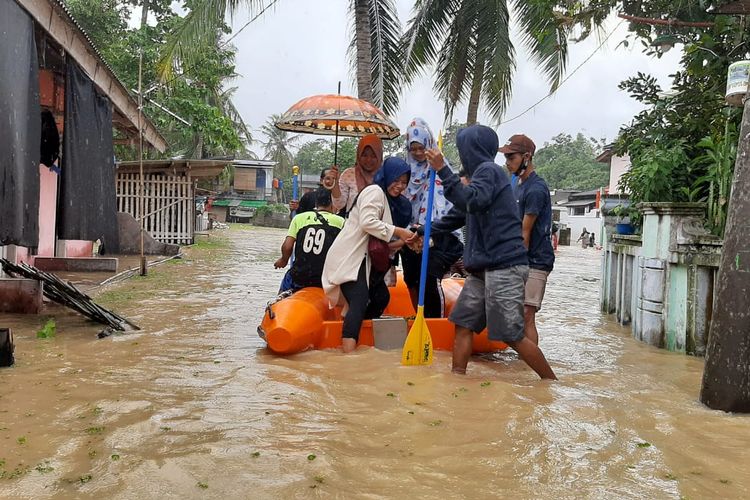 Warga Kampung Dadap, Desa Cijeruk, Kecamatan Kibin meneronos banjir menggunakan perahu karet menuju TPS