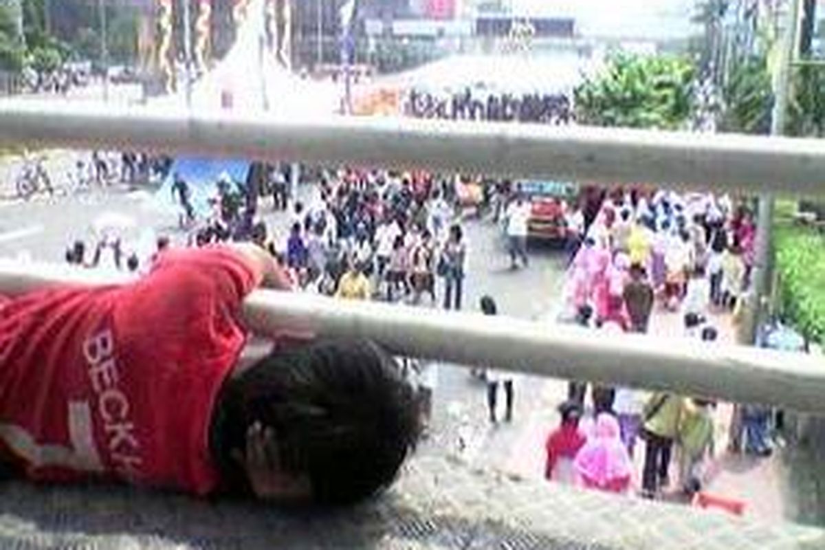 Nur Cahaya, pengemis cilik, di jembatan penyeberangan Sarinah Thamrin, Jakarta, menyaksikan perayaan Hari Anak Nasional dari kejauhan, Minggu (27/7). 