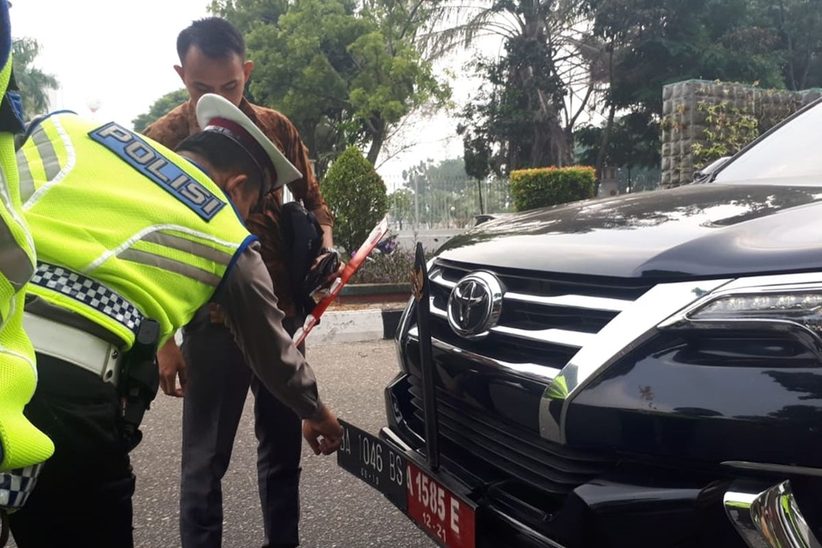 Petugas Ditlantas Polda Riau saat menilang mobil dinas anggota dewan Sumbar, yang menggunakan pelat palsu.