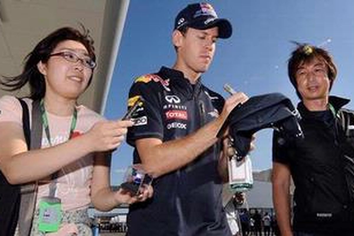 Pebalap Red Bull Racing, Sebastian Vettel, melayani permintaan fansnya, dengan membubuhkan tanda tangan.