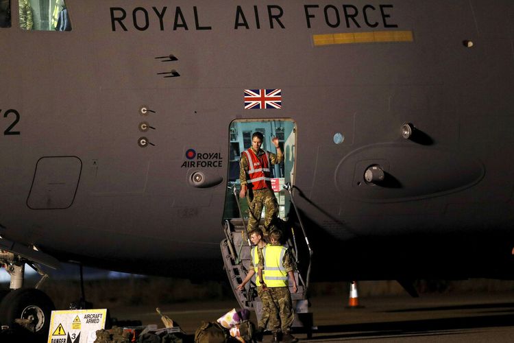 Personel militer Inggris meninggalkan sebuah pesawat C-17 di RAF Brize Norton, Oxfordshire, Minggu malam, 29 Agustus 2021. 