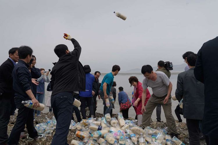 Aktivis pembelot Korea Utara melemparkan botol-botol berisi beras, uang dan USB dari Pulau Ganghwa, barat Seoul, Selasa (1/5/2018). Kegiatan itu dilakukan secara rutin dengan harapan bisa terbawa arus hingga ke negeri asal mereka dan mengubah cara berpikir rakyat Korea Utara yang selama ini terbelenggu.