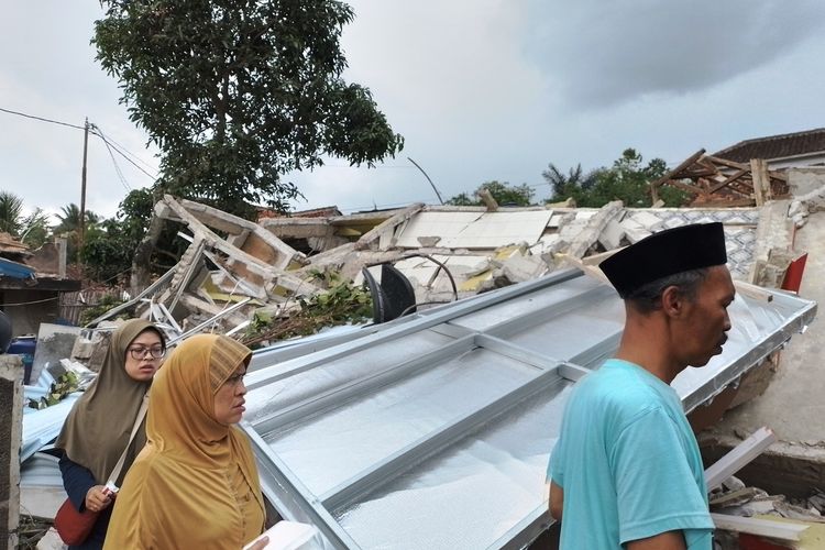 Sejumlah warga di Desa Cibulakan, Cianjur, Jawa Barat, melintas di depan reruntuhan bangunan yang ambruk diguncang gempa magnitdo 5,6.