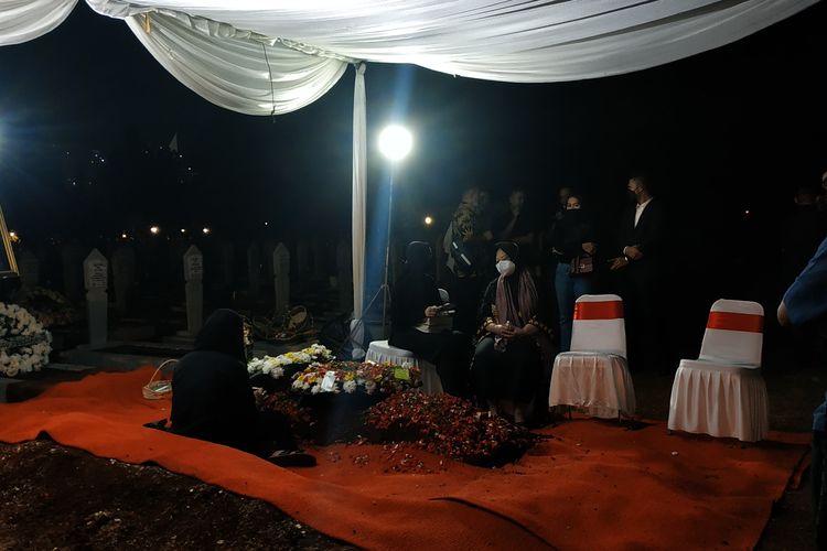 Istri Tjahjo Kumolo, Erni Guntarti, terduduk di tepi pusara suaminya di Taman Makam Pahlawan Kalibata, Jumat (1/7/2022) selepas para pelayat pulang.