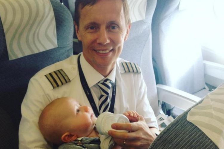 Kapten Tom Nystrom saat membantu memberi makan seorang bayi di atas kabin sebuah pesawat milik maskapai Finnair.