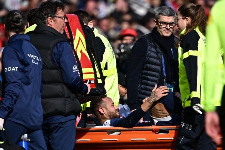 Neymar ditandu keluar lapangan usai mengalami cedera pergelangan kaki dalam laga pekan ke-24 Liga Perancis 2022-2023 antara PSG vs Lille di Stadion Parc des Princes, Minggu (19/2/2023). (Photo by Anne-Christine POUJOULAT / AFP)